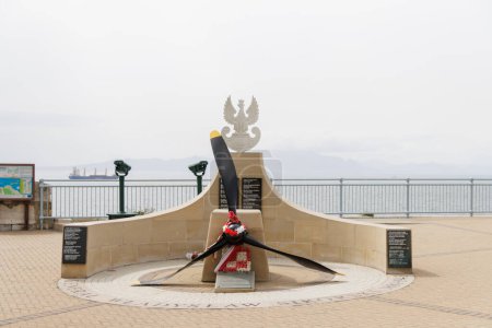 A large propeller is on display in front of a monument. The monument is surrounded by a circular walkway and has a plaque with the words "Polish Navy" on it