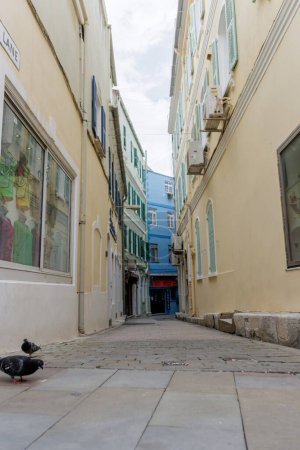 Une ruelle étroite avec un bâtiment bleu d'un côté et un bâtiment jaune de l'autre. L'allée est vide et a une atmosphère calme et paisible