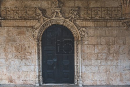 Foto de Puertas dobles de madera negra con marco decorativo y pared de piedra - Imagen libre de derechos