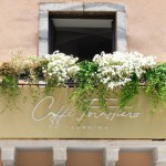 Taormina , Italy - August 9 2023: Flower box with blooming white plants hanging from the window in a building in Taormina, Sicily. Sign of Cafe Forasterio