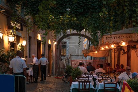 Téléchargez les photos : Rome, Italie - 15 août 2023 : Restaurant avec sièges extérieurs le soir. Serveurs servant des aliments à l'extérieur - en image libre de droit