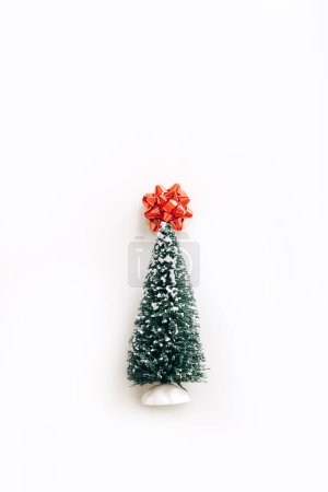 Photo for Lovely artificial mini Christmas tree with red bow on top over white background - Royalty Free Image