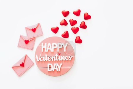 Foto de Wooden Happy Valentines Day message with felt envelopes and red hearts on white background, top view - Imagen libre de derechos