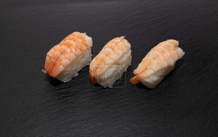 Sushi nigiri z gotowanymi krewetkami na czarnym talerzu