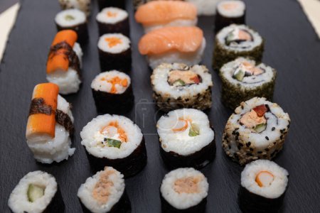 Sushi set in a plastic tray, food sticks and wasabi and ginger packets. Sushi nigiri, hosomaki, California,