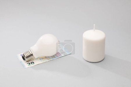 Foto de Vela blanca y bombilla en la parte superior de los billetes de 20 euros, fondo gris - Imagen libre de derechos