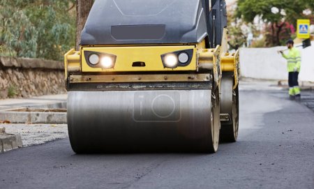 Photo for Road roller and asphalt paver machine at the construction site, with hot concrete and smoke - Royalty Free Image