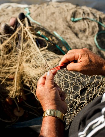 Foto de Pescador mediterráneo, costa malagueña, teje y repara una red de pesca - Imagen libre de derechos