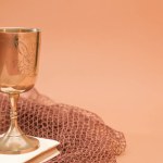 golden chalice on top of communion book with fishing net on brown background