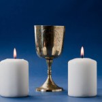 beautiful christian chalice surrounded by candles and blue background