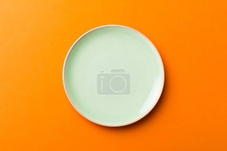 Foto de Vista superior de aislado de fondo de color vacío placa verde redonda para la comida. Plato vacío con espacio para su diseño. - Imagen libre de derechos