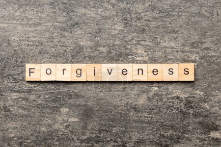 Vergebungswort auf Holzblock geschrieben. Vergebungstext auf dem Tisch, Konzept.