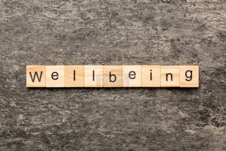 Photo for Wellbeing word written on wood block. Wellbeing text on cement table for your desing, concept. - Royalty Free Image
