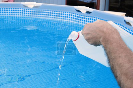 Foto de Limpieza de una piscina marco de PVC de algas mediante el vertido de perhidrol, Concepto de servicios de limpieza. - Imagen libre de derechos