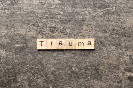 Trauma-Wort auf Holzblock geschrieben. Trauma-Text auf dem Tisch, Konzept.