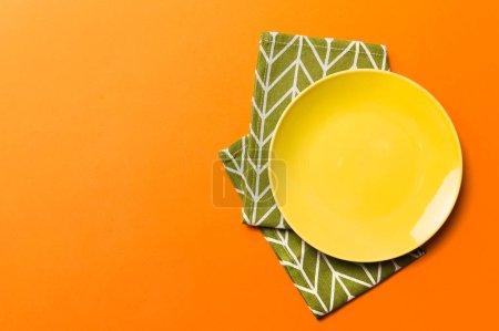 Photo for Top view on colored background empty round yellow plate on tablecloth for food. Empty dish on napkin with space for your design. - Royalty Free Image