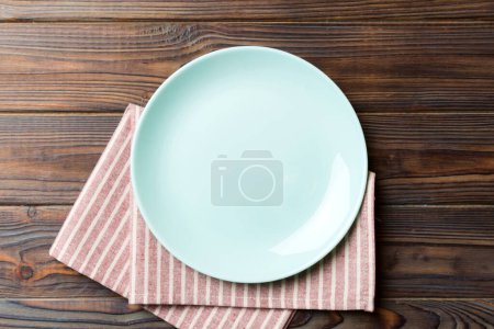 Vista superior sobre fondo de color vacío redondo Placa azul sobre mantel para la comida. Plato vacío en servilleta con espacio para su diseño.