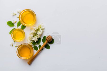 tarro de miel con flores y hojas de acacia. miel fresca vista superior plana laico.