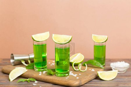 Photo for Sweet refreshing mint liqueur, with ice and mint leaves on table background, Shots with lime slice and mint flat lay. - Royalty Free Image