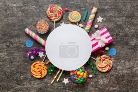 Photo for Flat lay holiday composition. Paper blank, lollipop, birthday decorations on Colored background. Top view, copy space for text. - Royalty Free Image