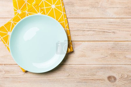 Vista superior sobre fondo de color vacío redondo Placa azul sobre mantel para la comida. Plato vacío en servilleta con espacio para su diseño.