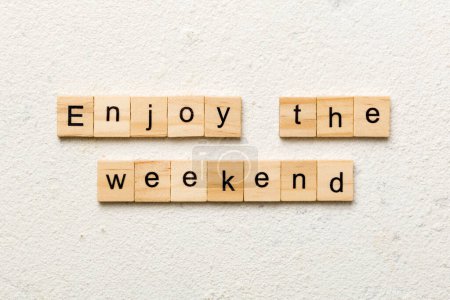 Profitez du mot de week-end écrit sur un bloc de bois. Profitez du texte du week-end sur table en ciment pour votre desing, concept Top view.