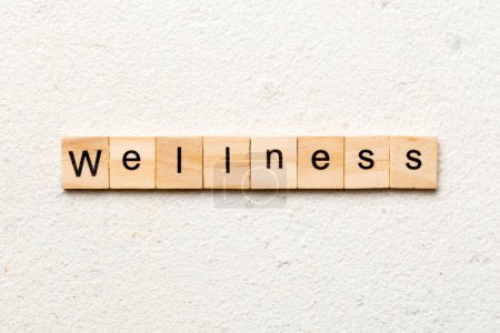Wellness-Wort auf Holzblock geschrieben. Wellness-Text auf Zementtisch für Ihre Gestaltung, Ihr Konzept.