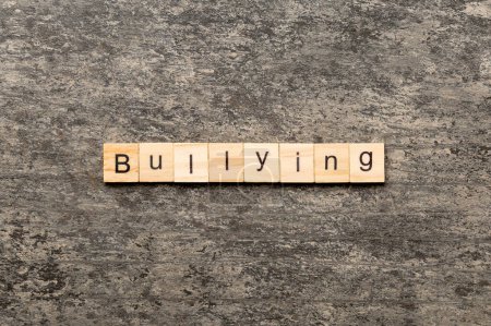 Bullying word written on wood block. Bullying text on cement table for your desing, concept.