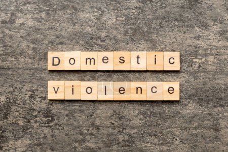 Domestic violence word written on wood block. Domestic violence text on cement table for your desing, Top view concept.