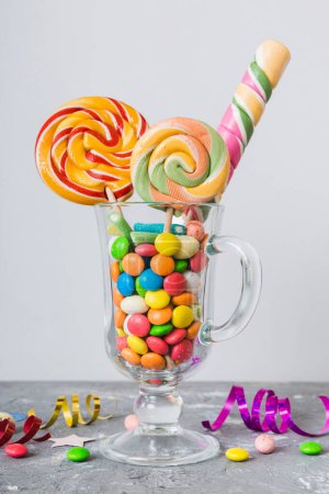Photo for Colorful candies in cup on table on light background background. Large swirled lollipops. Creative concept of a jar full of delicious sweets from the candy store. - Royalty Free Image