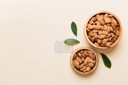 Téléchargez les photos : Fresh healthy Almond in bowl on colored table background. Top view. - en image libre de droit
