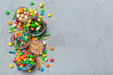bonbons ronds de différentes couleurs dans un bol et des bocaux. Vue du dessus des bonbons et des bonbons de grande variété avec espace de copie.