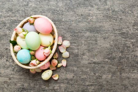 Photo for Happy Easter. Easter eggs in basket on colored table with yellow roses. Natural dyed colorful eggs background top view with copy space. - Royalty Free Image