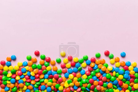 Téléchargez les photos : Collection mixte de bonbons colorés, sur fond coloré. Couché à plat, vue de dessus. cadre de bonbons enduits de chocolat coloré. - en image libre de droit