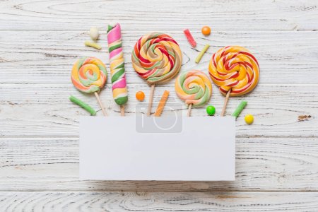 Photo for Flat lay holiday composition. Paper blank, lollipop, birthday decorations on Colored background. Top view, copy space for text. - Royalty Free Image