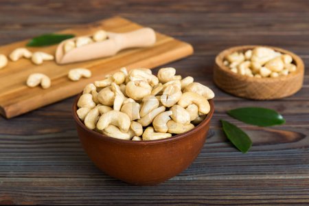 Téléchargez les photos : Cashew nuts in wooden bowl on table background. top view. Space for text. Healthy food - en image libre de droit
