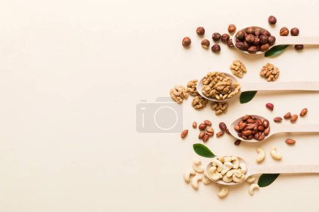 Foto de Nueces mezcladas en cuchara de madera blanca. Mezcla de varias nueces sobre fondo de color. pistachos, anacardos, nueces, avellanas, cacahuetes y nueces de Brasil. - Imagen libre de derechos
