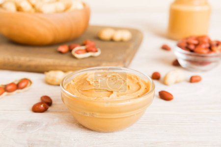 Photo for Bowl of peanut butter and peanuts on table background. top view with copy space. Creamy peanut pasta in small bowl. - Royalty Free Image