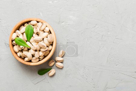 Fresh healthy Pistachios in bowl on colored table background. Top view. Healthy eating concept. Super foods.
