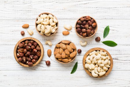 Photo for Assortment of nuts in wooden bowl on colored table. Cashew, hazelnuts, walnuts, almonds. Mix of nuts Top view with copy space. - Royalty Free Image