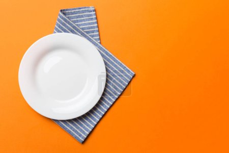 Photo for Top view on colored background empty round white plate on tablecloth for food. Empty dish on napkin with space for your design. - Royalty Free Image