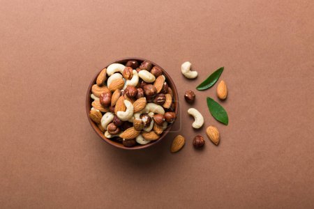Photo for Assortment of nuts in wooden bowl on colored table. Cashew, hazelnuts, walnuts, almonds. Mix of nuts Top view with copy space. - Royalty Free Image