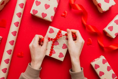 Foto de Women hands pack gifts and make decorations for the holiday, top view. Birthday and valentine present. - Imagen libre de derechos