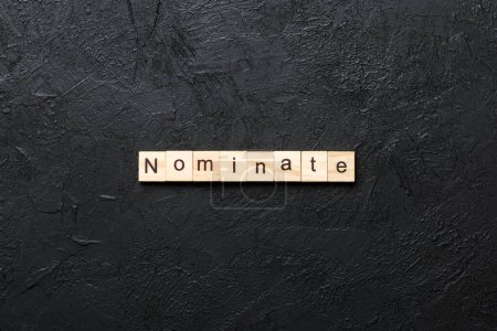 nominate word written on wood block. nominate text on table, concept.
