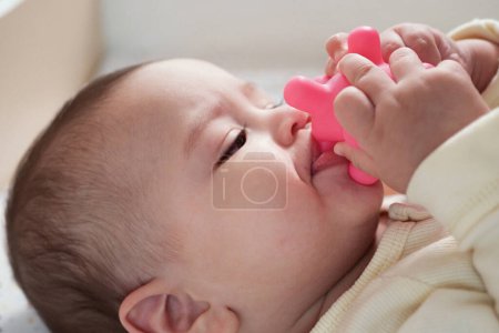 Foto de Lindo adorable bebé recién nacido jugando con colorido juguete sonajero. bebé con mordedor. seis meses de edad hermoso bebé retrato en blanco con mordedor juguete. - Imagen libre de derechos