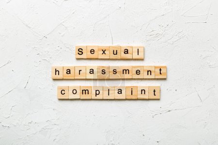 Beschwerdewort sexuelle Belästigung auf Holzklotz geschrieben. Beschwerdetext für sexuelle Belästigung auf dem Tisch, Konzept.