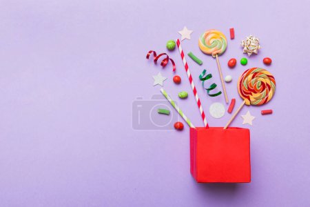 Foto de Gift box in corner full of assorted traditional candies falling out on colored background with copy space. Happy Holidays sale concept. - Imagen libre de derechos