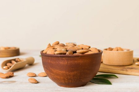 Fresh healthy Almond in bowl on colored table background. Top view.