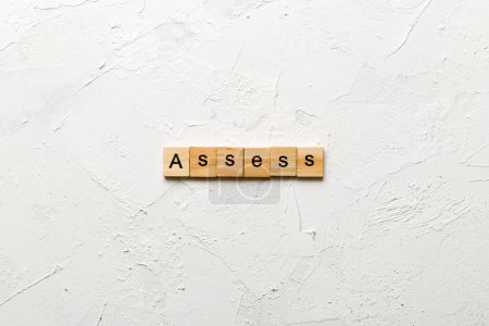 Photo for ASSESS word written on wood block. ASSESS text on cement table for your desing, concept. - Royalty Free Image