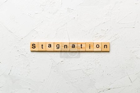 Stagnation Wort auf Holzblock geschrieben. Stagnationstext auf Zementtisch für Ihre Gestaltung, Ihr Konzept.